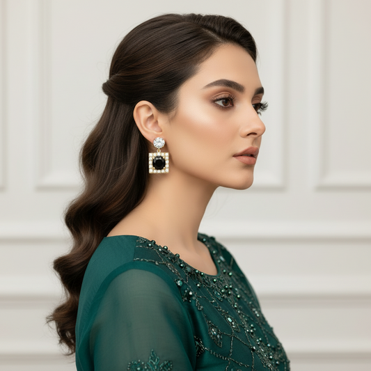 Woman wearing a green dress with intricate detailing and a pair of earrings.