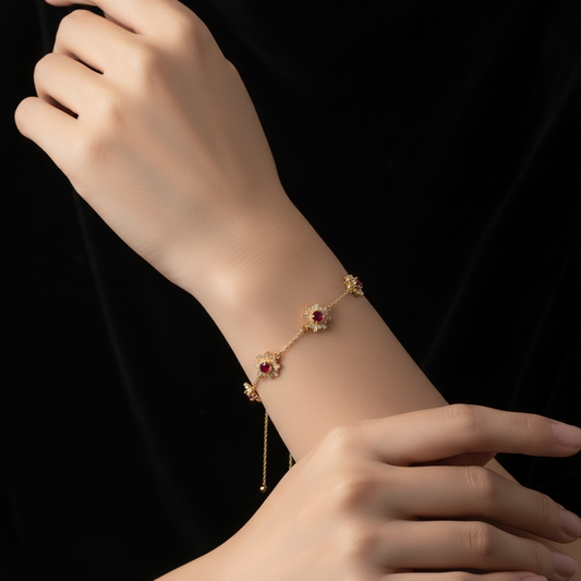 Gold bracelet with red gemstones on a wrist against a black background