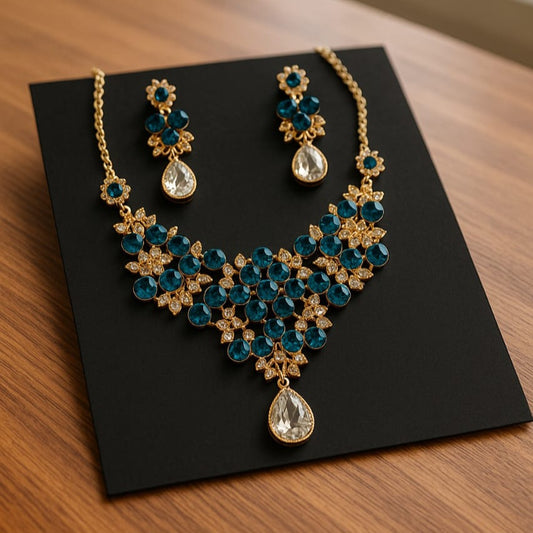 Gold and blue gemstone necklace and earrings on a black stand