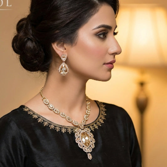 Woman wearing a black outfit with a gold necklace and earrings against a warm background