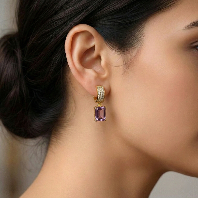 Close-up of a woman wearing a gold earring with a purple gemstone.
