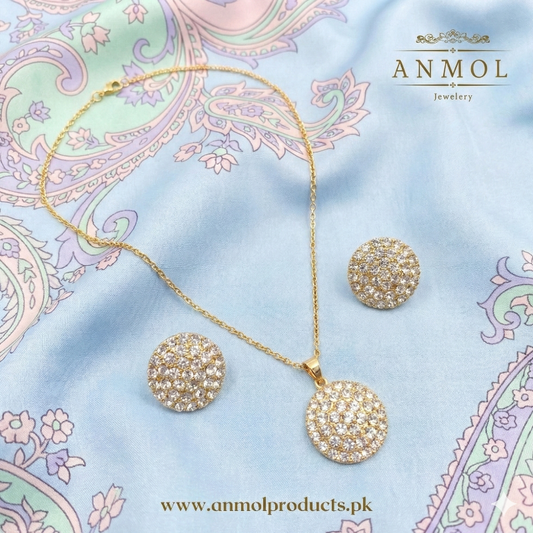 Gold jewelry set with necklace and earrings on a decorative fabric background, featuring the brand 'Anmol Jewelry'.