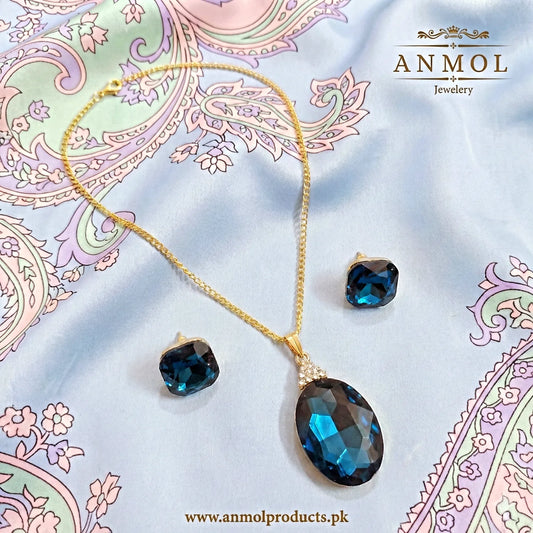 Jewelry set with blue gemstones on a decorative fabric background, featuring the brand 'Anmol Jewelry'.