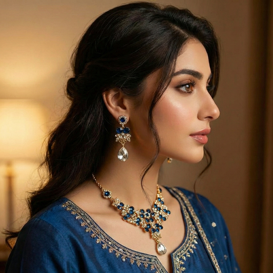Woman wearing a blue and gold necklace and earrings in a warm-toned room.