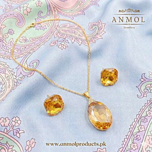 Gold jewelry set with yellow gemstones on a decorative fabric background, featuring the brand 'Anmol Jewelry'.