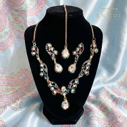 Jewelry set on a black stand with 'Anmol' branding against a paisley patterned background