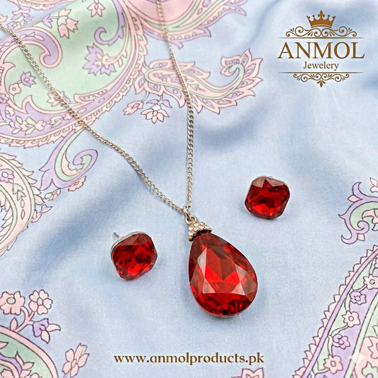 Red teardrop necklace and earrings on a decorative fabric background with ANMOL Jewellery branding.